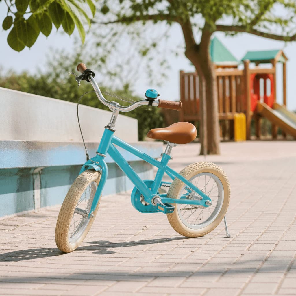Kleines türkisfarbenes Kinderrad auf dem Ständer auf einem sonnigen Spielplatzweg