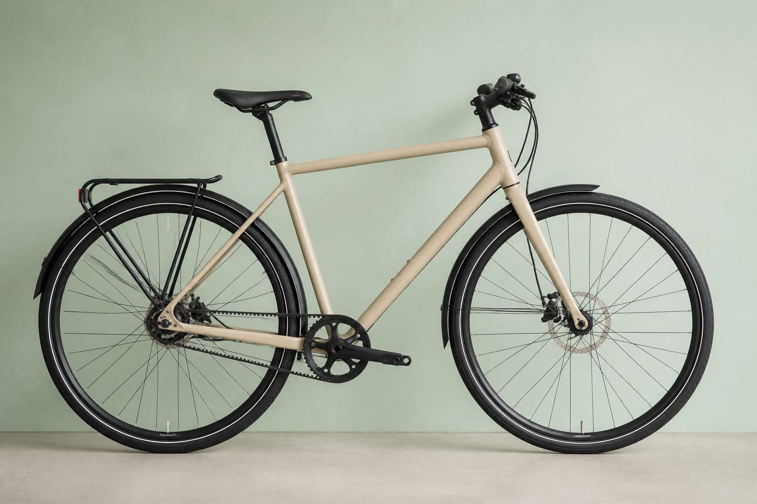 Trekkingrad in Sandbeige mit geradem Diamantrahmen und grauem Zahnriemen, von der Seite