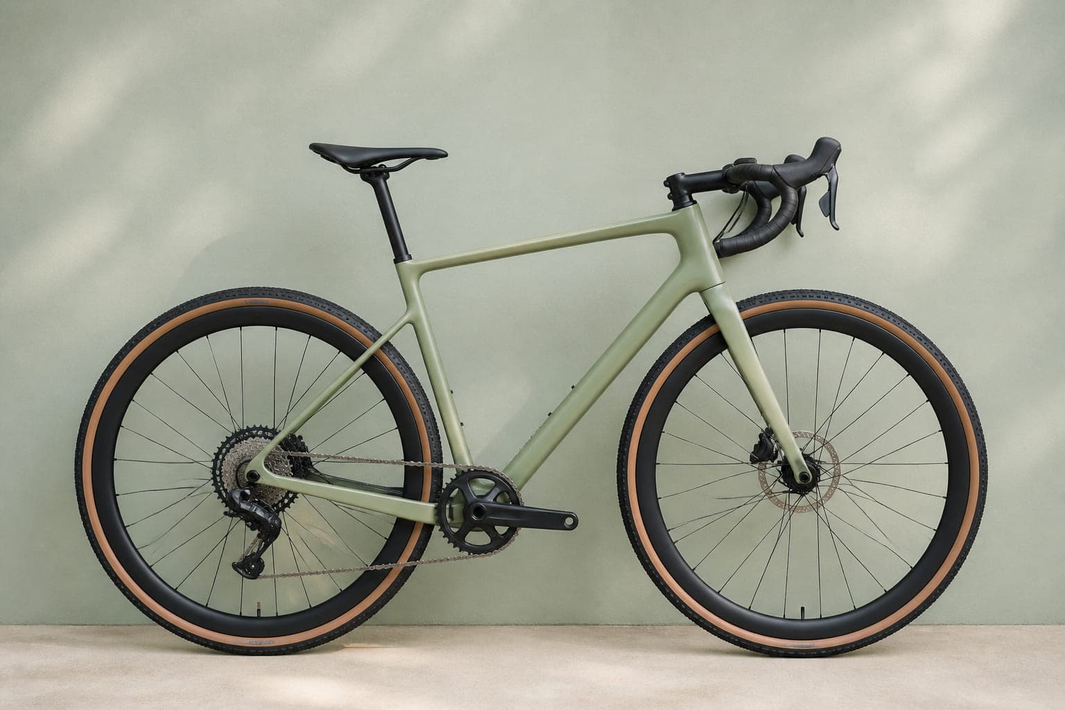 Leichtes Carbon-Gravelrad in blassem Salbeigrün mit Rennradlenker und einem Kettenblatt, von der Seite